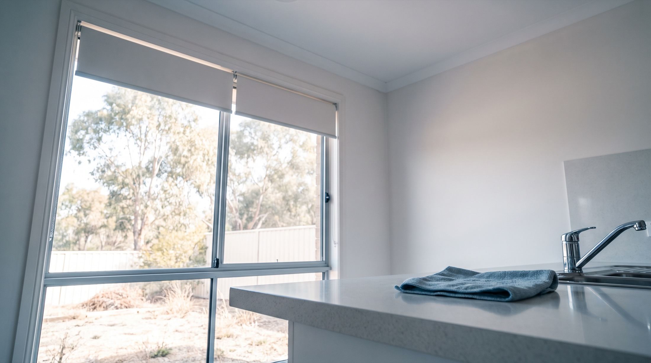 A kitchen benchtop and splashback with a folded cloth beside the tap