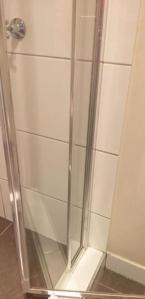 A shower screen with clear glass and a bare base track