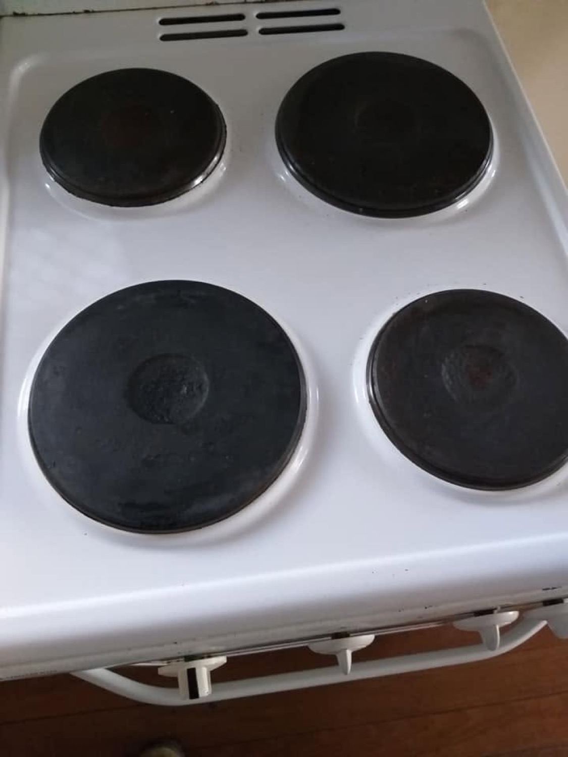 A white electric cooktop with bare enamel around the hotplates